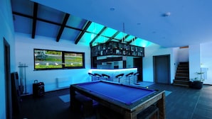 A pool table in a modern room with a bar area, a large window, and a staircase. - Apartment, 4BDR, shared pool (Sarajevo)