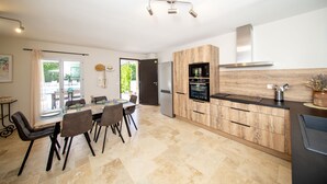 Una cocina moderna con comedor, que incluye una isla grande, electrodomésticos integrados y vistas al exterior.