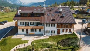 Une maison à deux étages, dotée d’un toit en pente, de grandes fenêtres et d’un balcon.