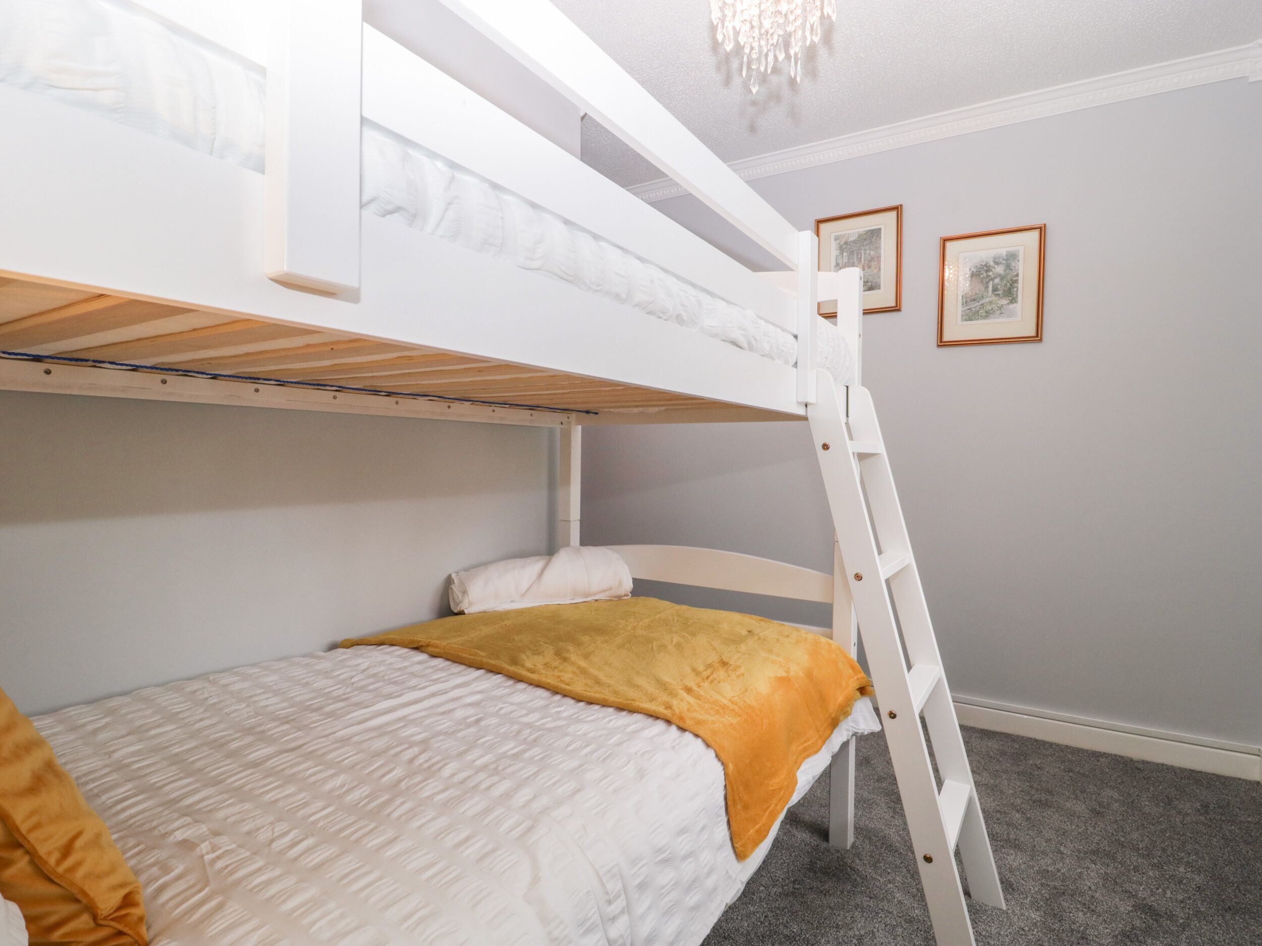Quarto com beliche, escada, cabeceira branca e carpete cinza.