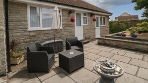 A stone house with a tiled roof, outdoor seating area with wicker furniture, and a bird bath. - Melita (Langport)