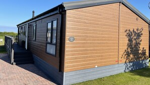 A modern building with a wooden exterior and a grey roof, featuring a staircase leading to a covered entrance. - Yorkshire View Lodge (York)