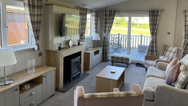 A cozy living room with a fireplace, seating area, and a view of the outdoors. - Yorkshire View Lodge (York)
