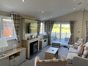 A cozy living room with a fireplace, seating area, and a view of the outdoors. - Yorkshire View Lodge (York)