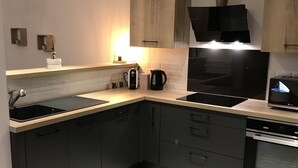 Una cocina moderna con armarios oscuros, un horno de acero inoxidable y una campana extractora negra.