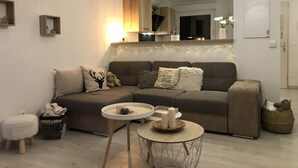 Una sala moderna con un sofá marrón, dos mesitas redondas y almohadones decorativos.