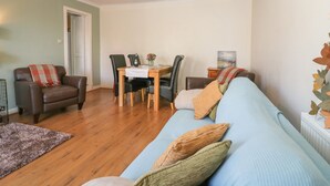 A living room with a sofa, chairs, a dining table, and a lamp. - Blue Skies Cottage (Arbroath)