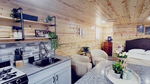 A cozy cabin-style room with a kitchen area, a dining table, and a bed. - Lake Victoria, Yellow Cabin , Panoramic views overlooking the lake (Alexandria)