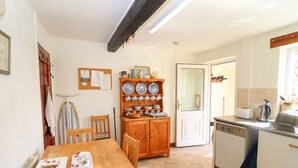 A kitchen with a wooden table, chairs, a cabinet with dishes, a toaster, and a coffee maker. - The Vinery (Gloucester)