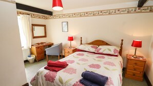A bedroom with a bed, two bedside tables with lamps, a chair, a desk, and a radiator. - The Vinery (Gloucester)
