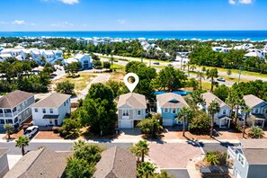 A residential area with multiple houses, a clear sky, and a body of water in the background. - ☀️ GOLF CART, HEATED POOL, Private Hot Tub, Bikes, Ping-Pong, Walk to Rosemary (Inlet Beach)