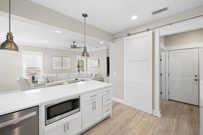 A modern kitchen with white cabinetry, a central island, and pendant lighting. - ☀️ GOLF CART, HEATED POOL, Private Hot Tub, Bikes, Ping-Pong, Walk to Rosemary (Inlet Beach)