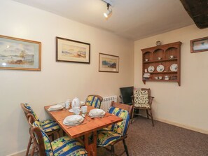 A dining area with a wooden table set for four, surrounded by chairs with floral upholstery. - Dollar Ward House Basement (Cirencester)