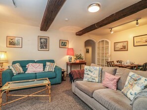 A cozy living room with two sofas, a coffee table, and a dining area with chairs and a table. - Dollar Ward House Basement (Cirencester)