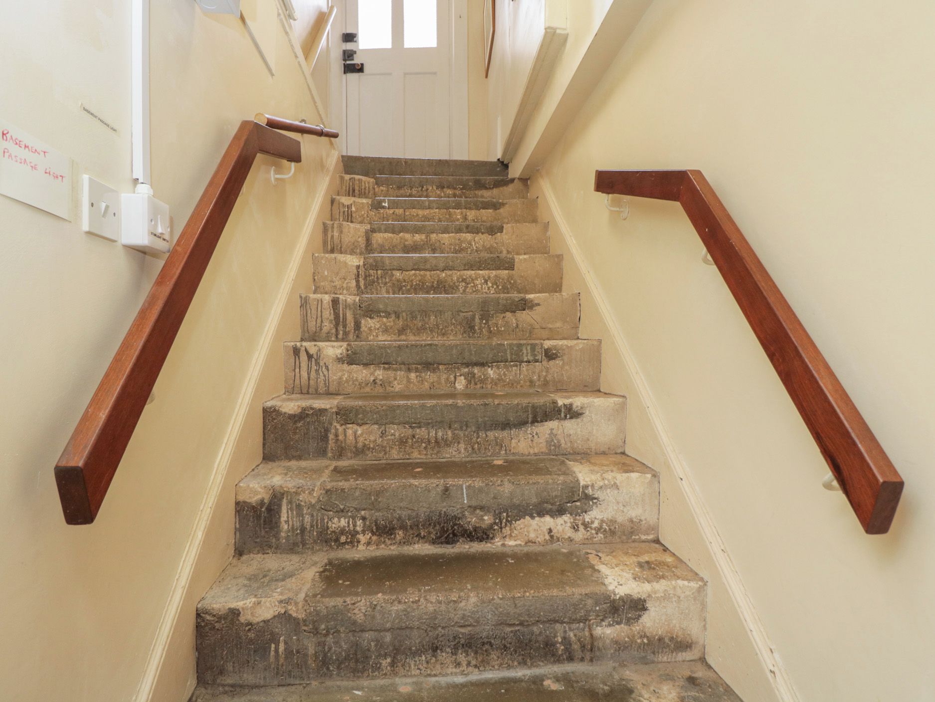 Eine Treppe mit hölzernen Geländern und einem Lichtschalter an der Wand.
