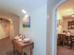 A hallway with a dining area featuring a wooden table, chairs, and a painting. - Dollar Ward House Basement (Cirencester)