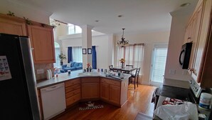 Una cocina moderna con armarios de madera, una isla integrada y un comedor con candelabro.