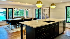 Une cuisine moderne dotée d’un grand îlot central, de meubles de couleur noire et d’un éclairage suspendu.