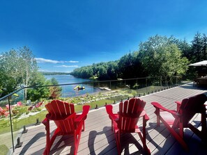 Une terrasse avec des chaises rouges donnant sur un lac, entourée de verdure.