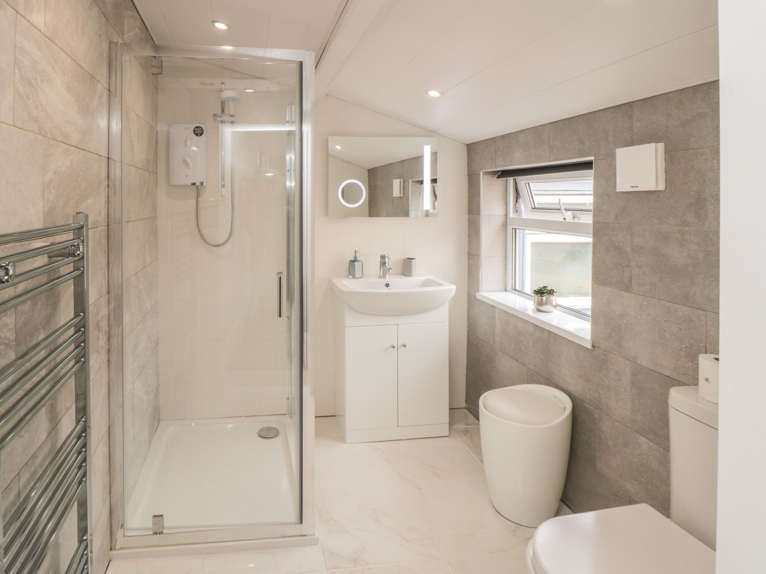 Un baño moderno con ducha envuelta en vidrio, un lavabo blanco y un inodoro.