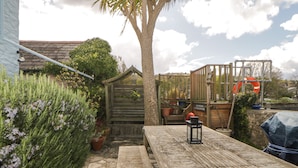 A wooden deck with a bench and a lantern, surrounded by potted plants and a wooden fence.