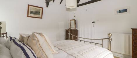 A bedroom with a bed, a dresser, a mirror, and a framed picture on the wall.