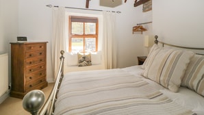 A bedroom with a bed, a dresser, a window with curtains, and a lamp.