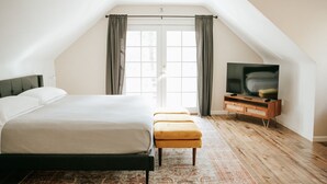 Un dormitorio con cama, televisor, ventilador de techo y ventana con cortinas.