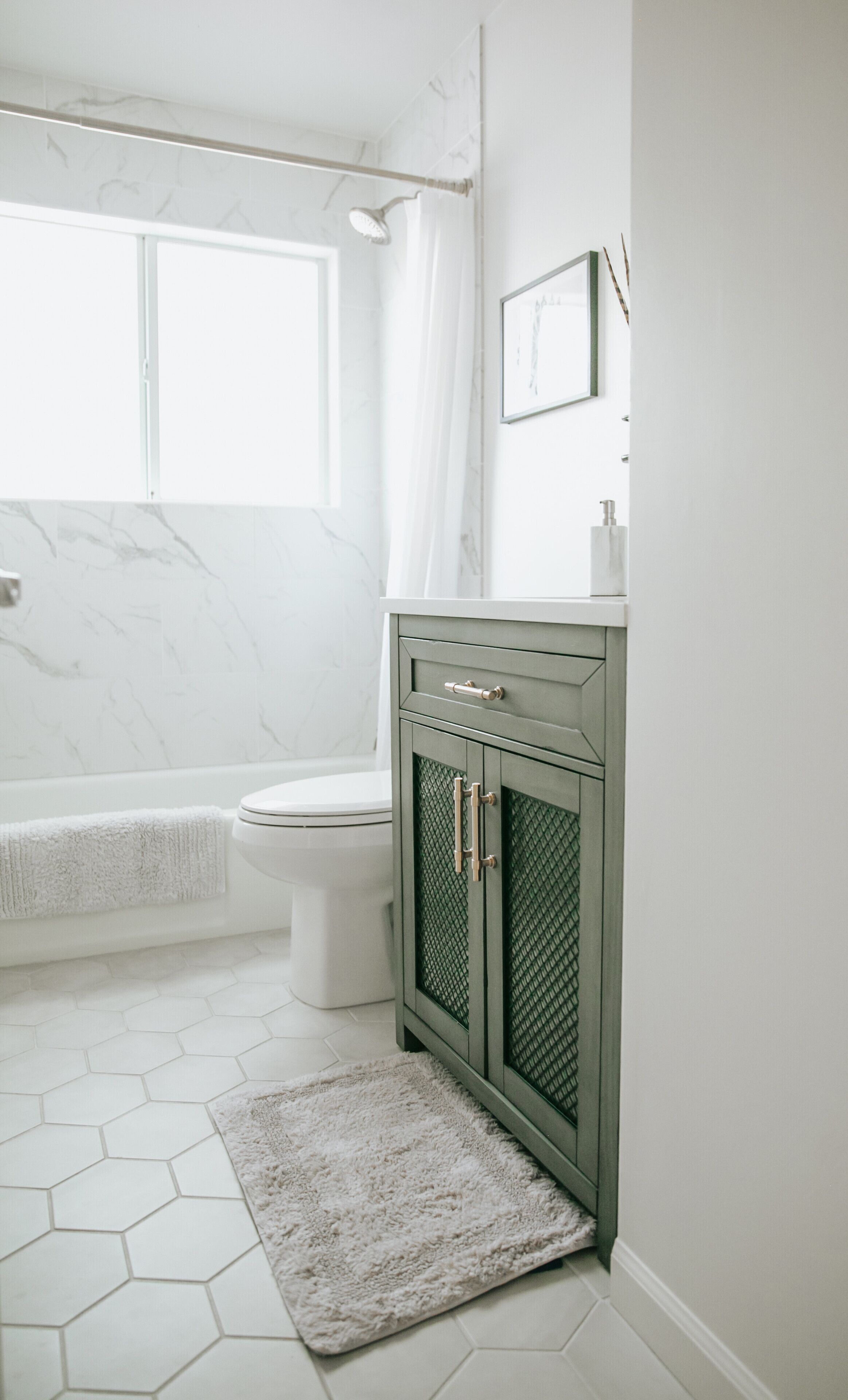 Ein Badezimmer mit Toilette, einer Badewanne und einem grünen Schrank mit Spiegel darüber.