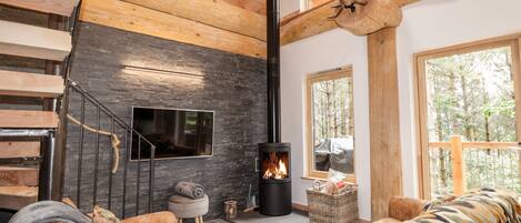 A modern interior with a fireplace, wooden staircase, and large windows.