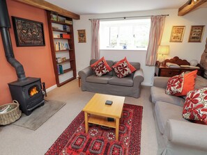 A cozy living room with a fireplace, a sofa, a coffee table, and a bookshelf.
