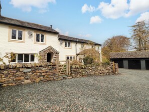 A two-story house with a stone wall entrance, a gravel driveway, and a garage.