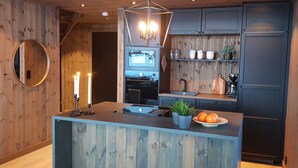 A modern kitchen with wooden accents, a central island, and a built-in oven. - Luxury cabin: Modern and stylish (Torpo)