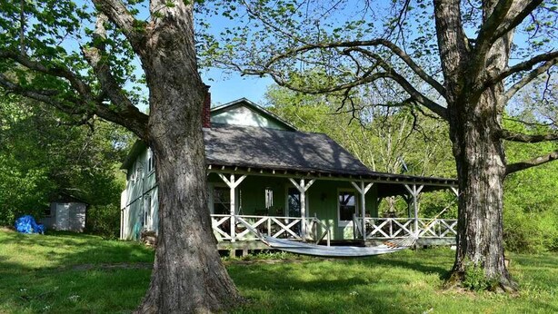 A rustic cabin with a porch, surrounded by trees and a grassy yard. - Rustic Tennessee Farmhouse on 100 acres of land (Bethpage)