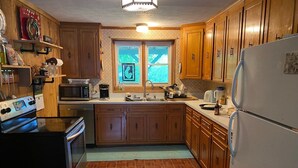 A compact kitchen with wooden cabinets, a refrigerator, a microwave, and a stove. - Rustic Tennessee Farmhouse on 100 acres of land (Bethpage)