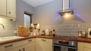 Una cocina moderna con horno empotrado, campana extractora de acero inoxidable y ventana sobre el fregadero.