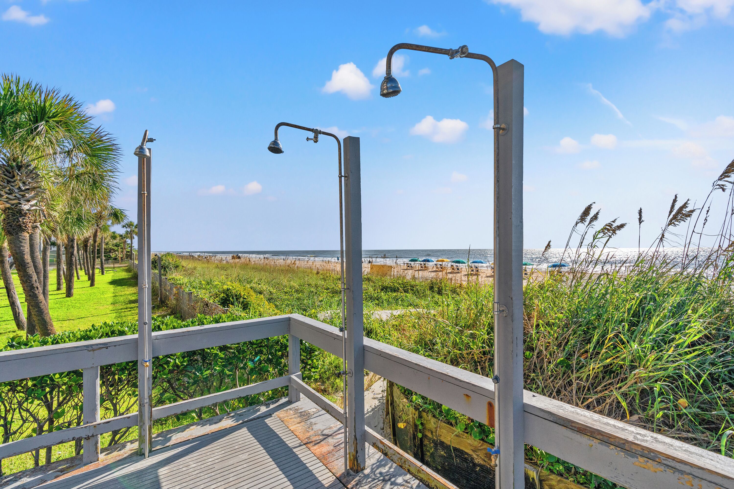 Une terrasse en bois avec des rampes en métal donnant sur une plage.