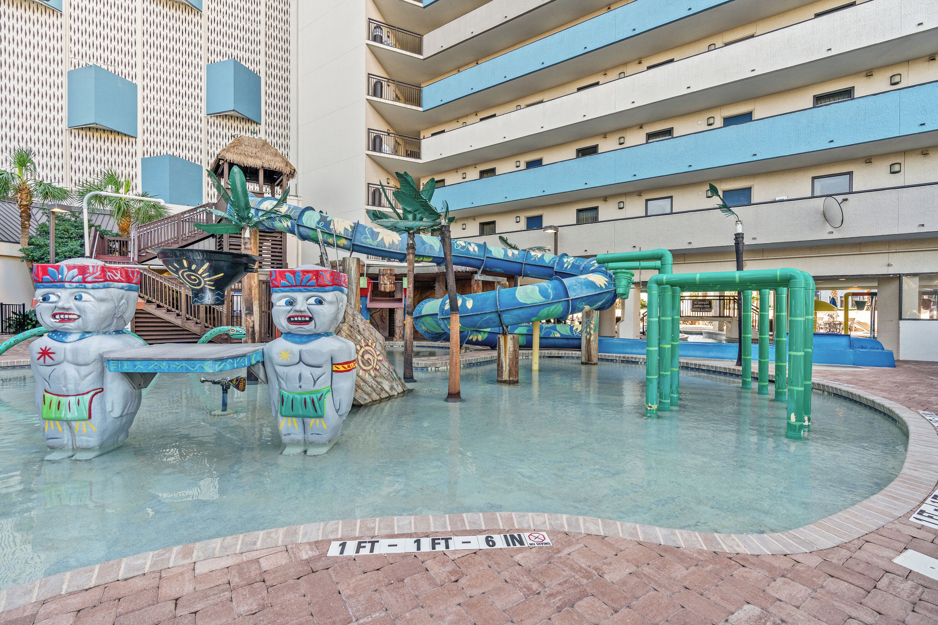 A water park with slides and a pool area, surrounded by a multi-story building.