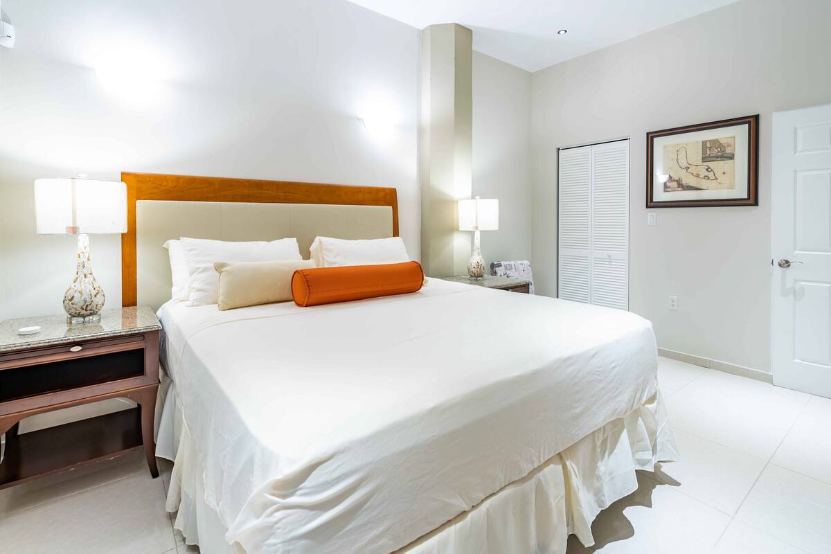 Una camera d'albergo con un letto grande, due comodini con lampade, una credenza e un quadro appeso alla parete.