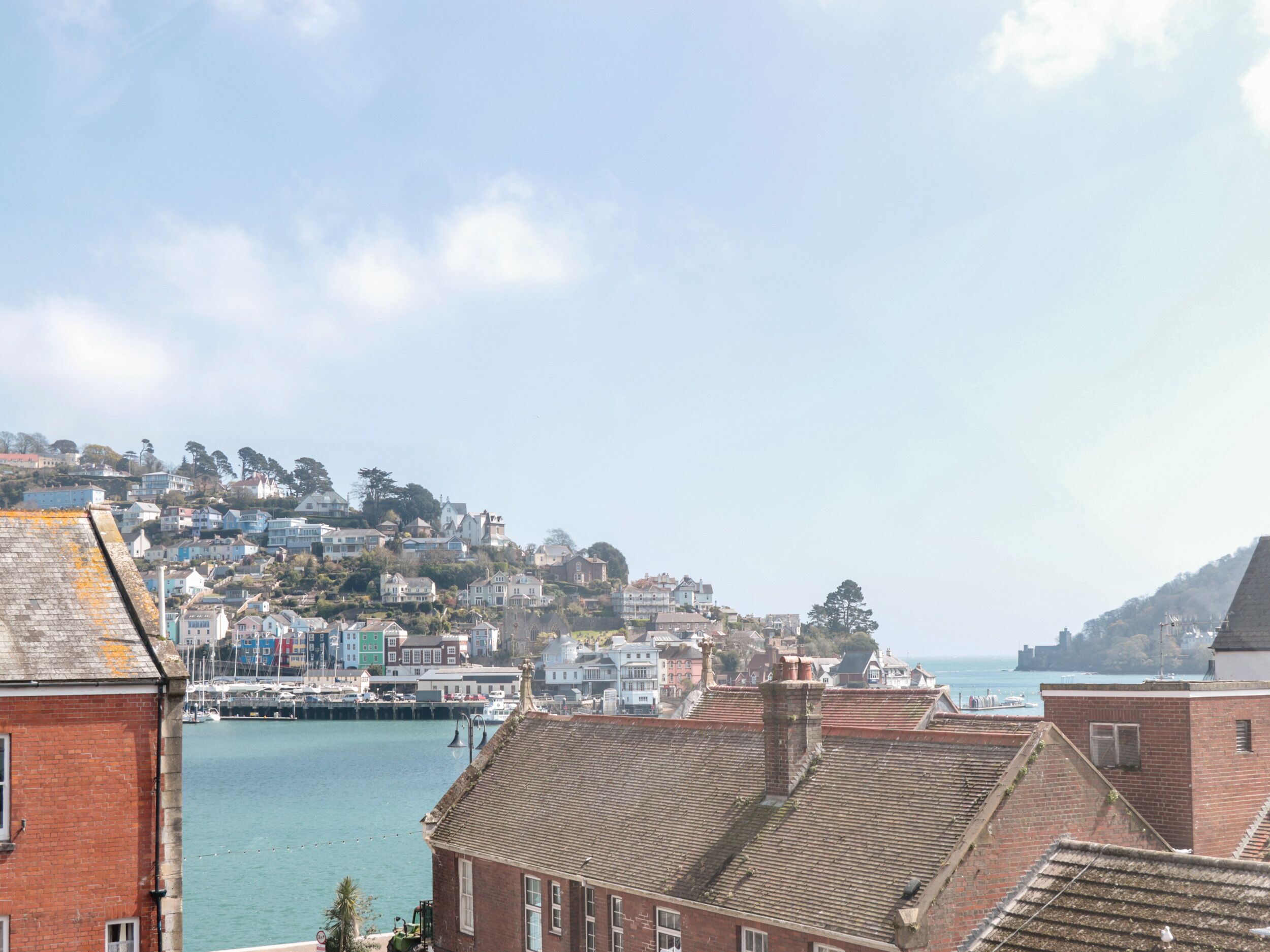 A coastal town with terraced houses, a marina, and a view of the sea.