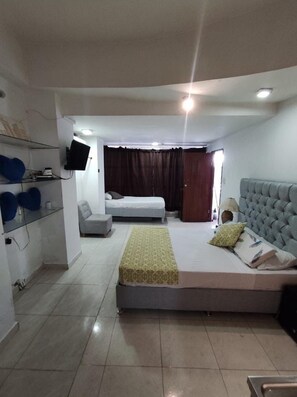 Una habitación de hotel con cama, sofá, televisión y una mesita.