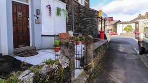 A stone building with a white door and a bench outside. - Neland View (Windermere)