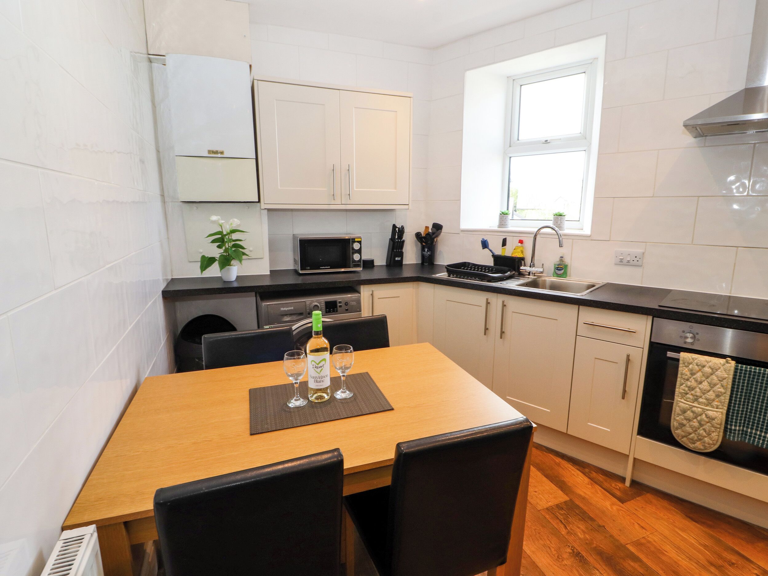 A compact kitchen with a dining table, chairs, a microwave, a sink, and a stove.