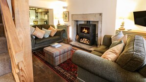 A cozy living room with a fireplace, wooden beams, a sofa, and a television.