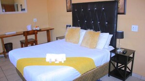 Quarto de hotel com uma cama grande, uma escrivaninha e uma mesa de cabeceira.
