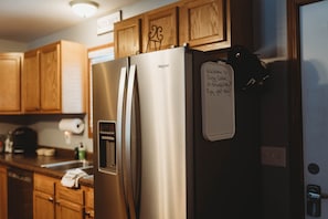 Un réfrigérateur en acier inoxydable dans une cuisine dotée de meubles en bois, avec un mot collé sur la porte.