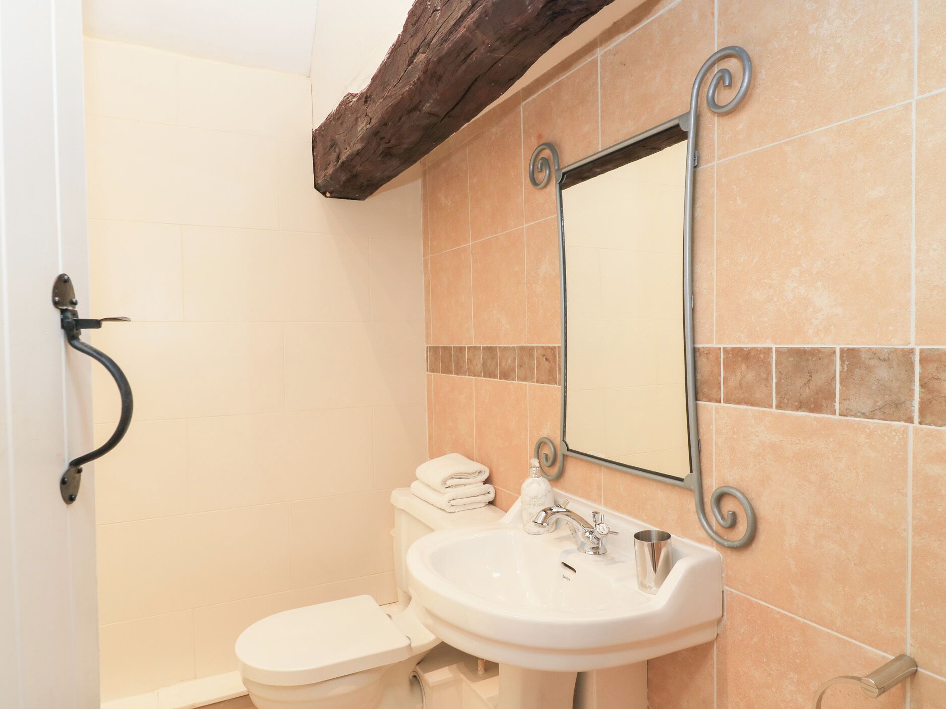 A bathroom with a toilet, sink, and mirror.