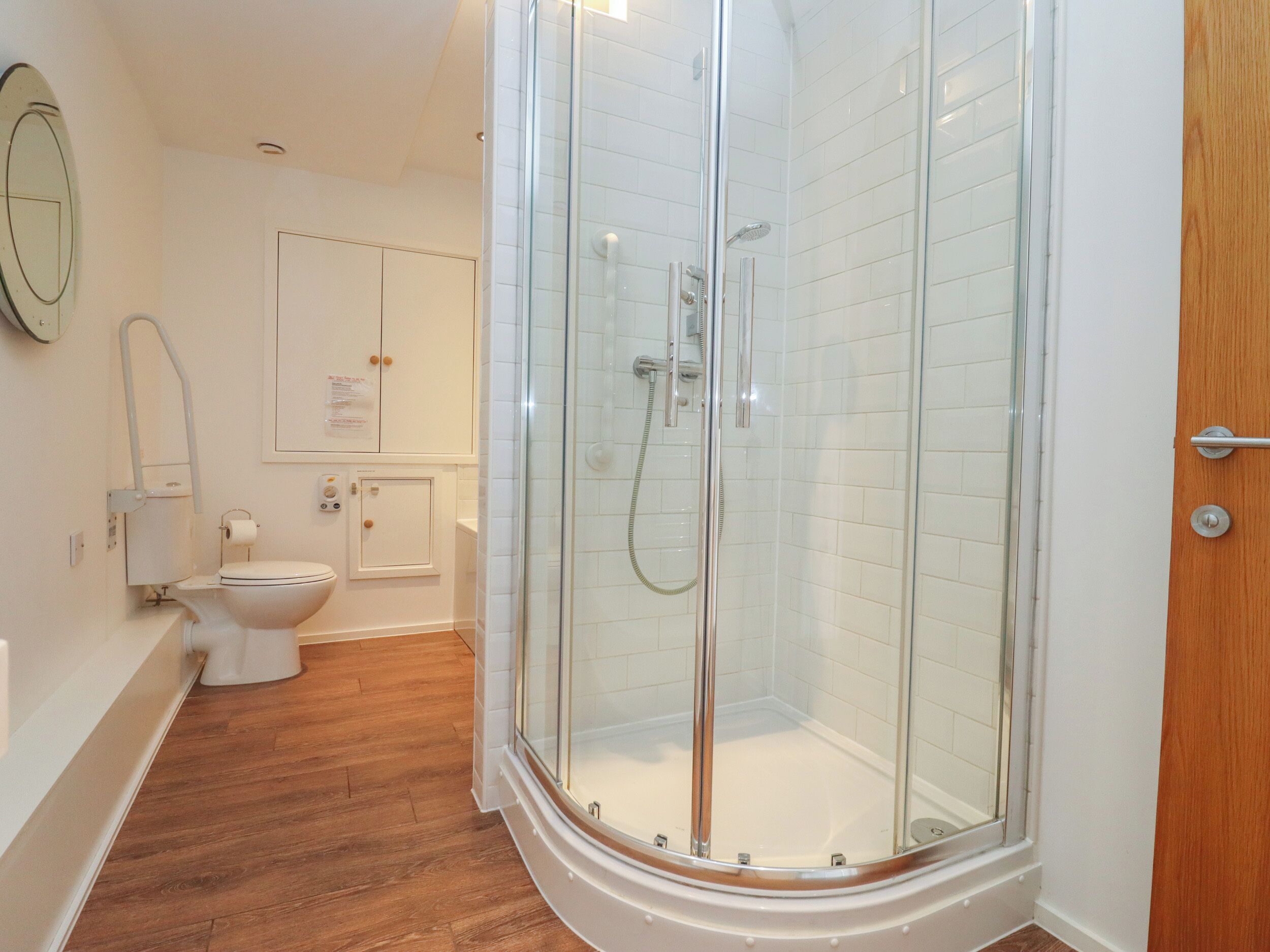 A modern bathroom with a glass-enclosed shower, a toilet, and a sink.