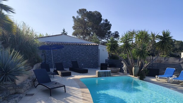 A swimming pool with lounge chairs and a stone wall. - Appart-hôtel-piscine (Fréjus)