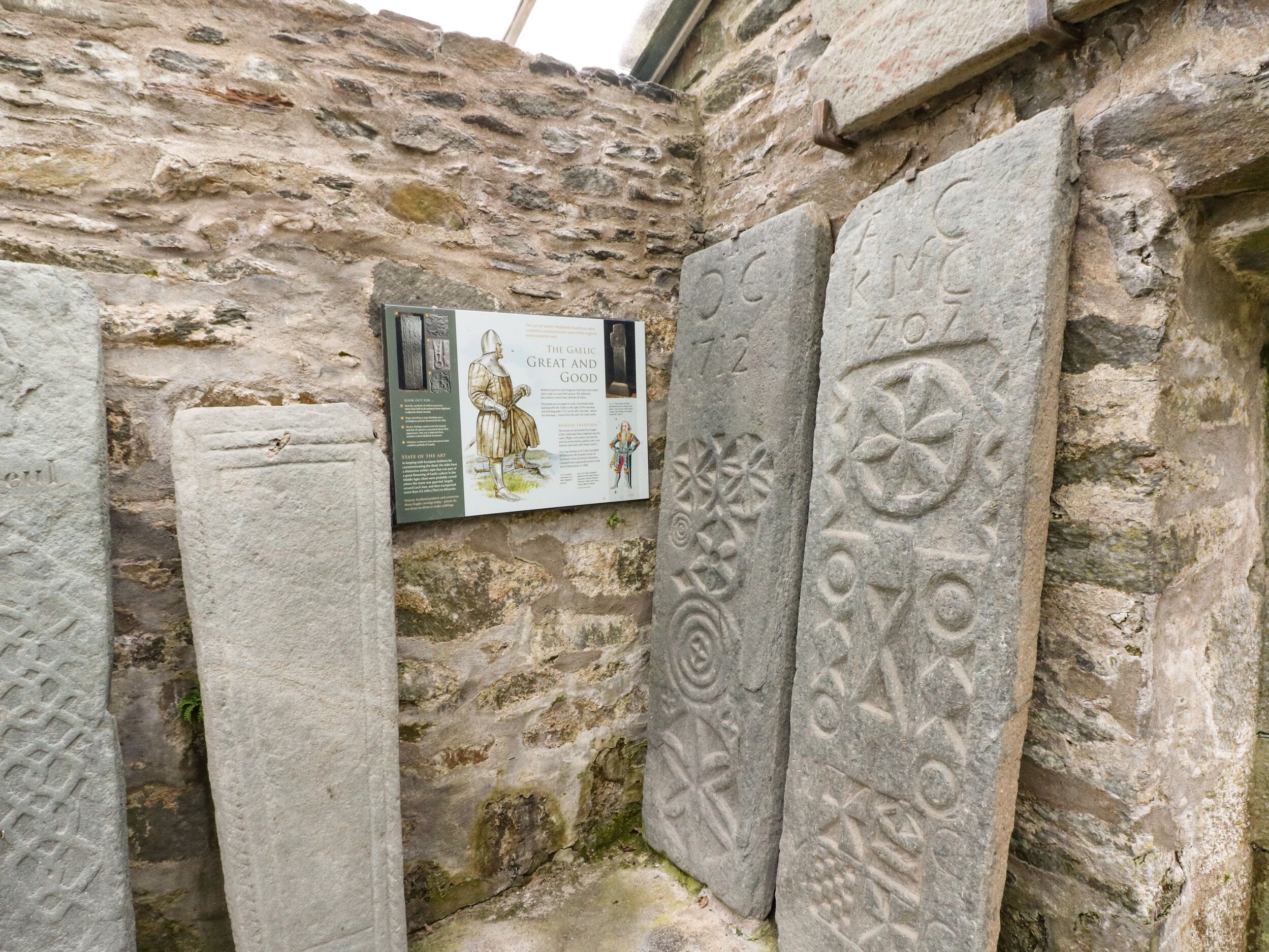 A stone wall with carved symbols and a mounted informational sign.